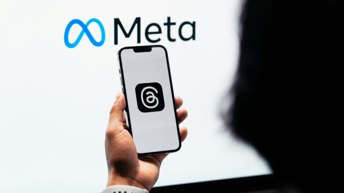 Person holding a phone displaying the Threads social media platform in front of the Meta logo as the company confirms plans to utilise content shared by its adult users in the EU (European Union) on platforms like Instagram and Facebook to train its AI models.